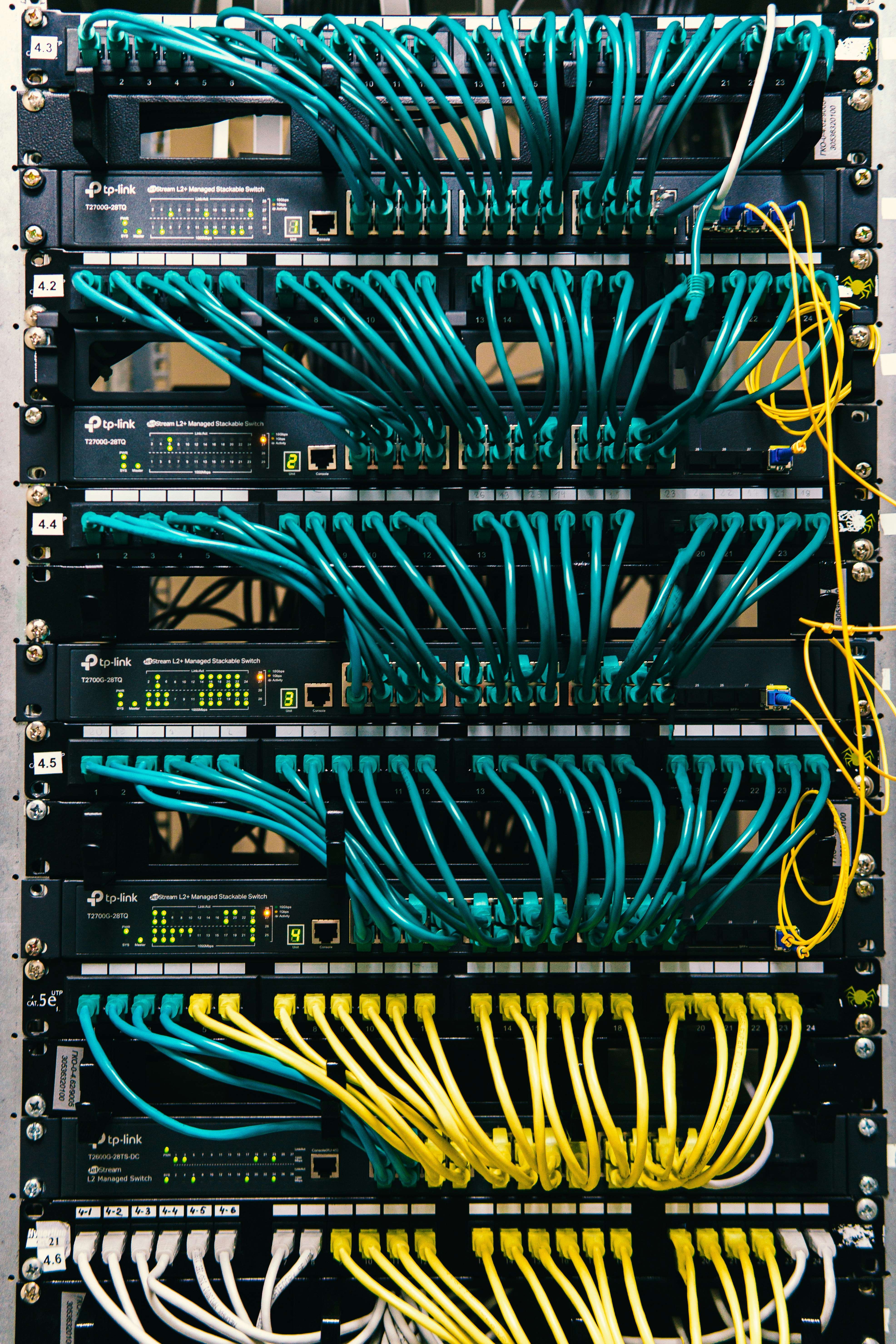 Netzwerkrack mit mehreren Schaltern und farbigen Ethernetkabeln.